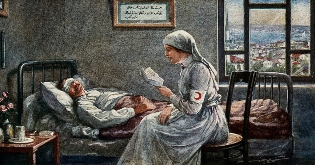 A nurse sitting beside a wounded man reading him a letter. Credit to Wellcome Collection/