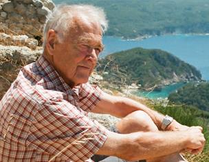 Old man seated near coastal landscape