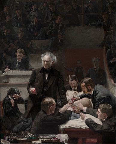 man lecturing while men cut into someone with a scalpel