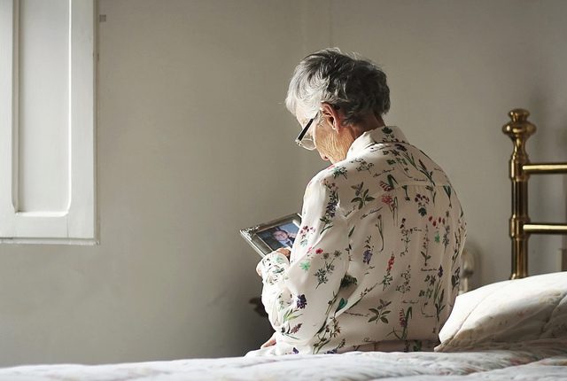 older woman sitting in bed looking at a photograph