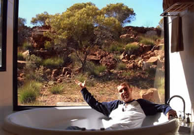 Craig sitting fully clothed in a luxury bathtub, opening his arms in a magnanimous gesture