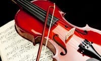 Photograph of a glossy violin on top of sheet music. Link to the Music Box section.