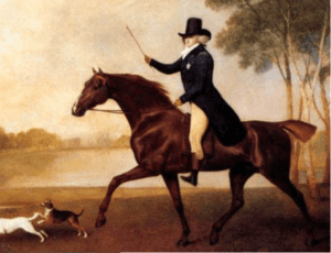Man with riding crop on horse with two dogs ahead of him
