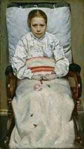 A sick girl sits propped up in a chair. She is holding a slightly crumpled flower in her hands.