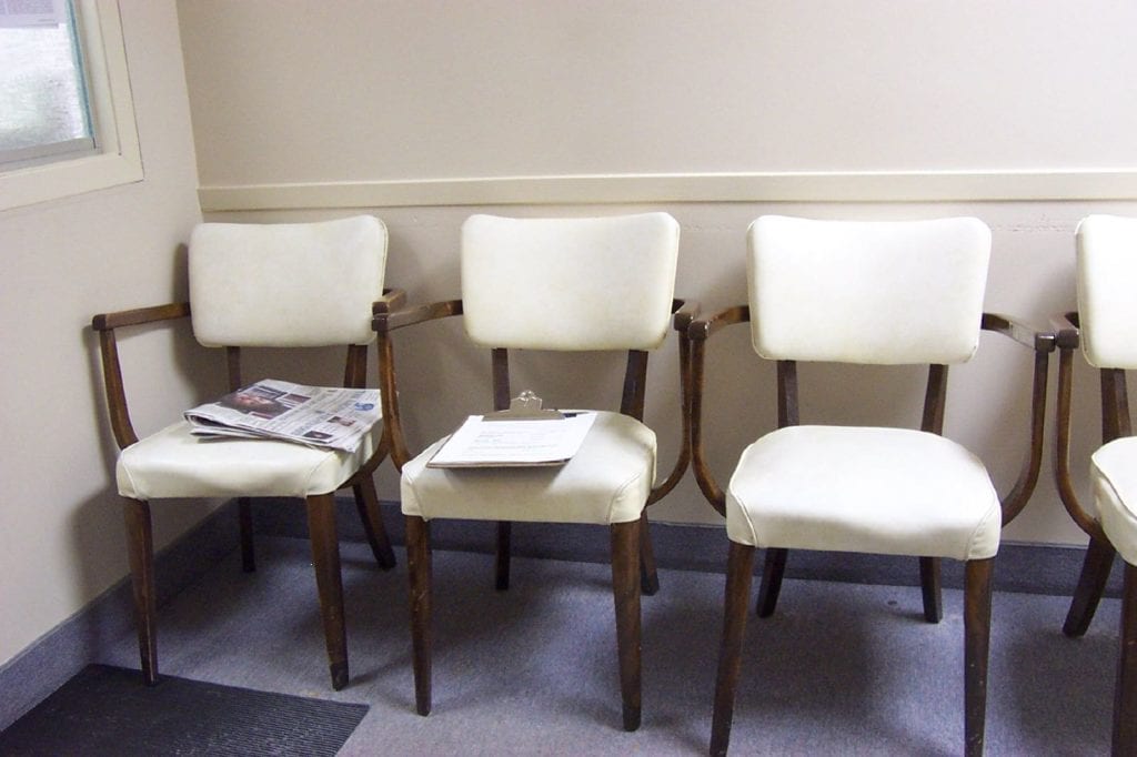Three white chairs are lined up in a medical facility.