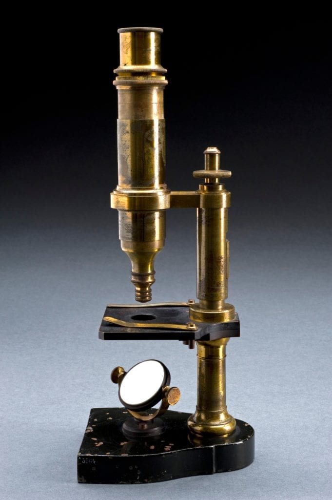 Photograph of a brass colored monocular microscope with reflecting mirror, similar to the one owned by the author at the Chicago Medical School