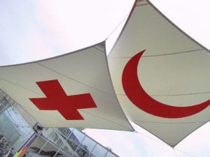 White flags with the red cross and red crescent are suspended against the shy