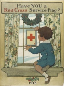A young boy hangs a red cross flag in his window