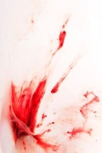 Photograph of menstrual blood flowing through water against a white background