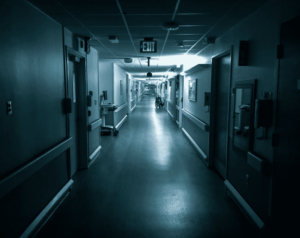 A hospital corridor in shadowy blue lighting.