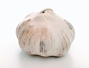 A whole clove of garlic on a white background