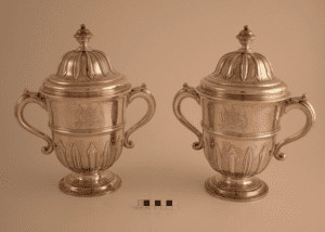 Two silver cups shaped like the tops of trophies with handles and lids